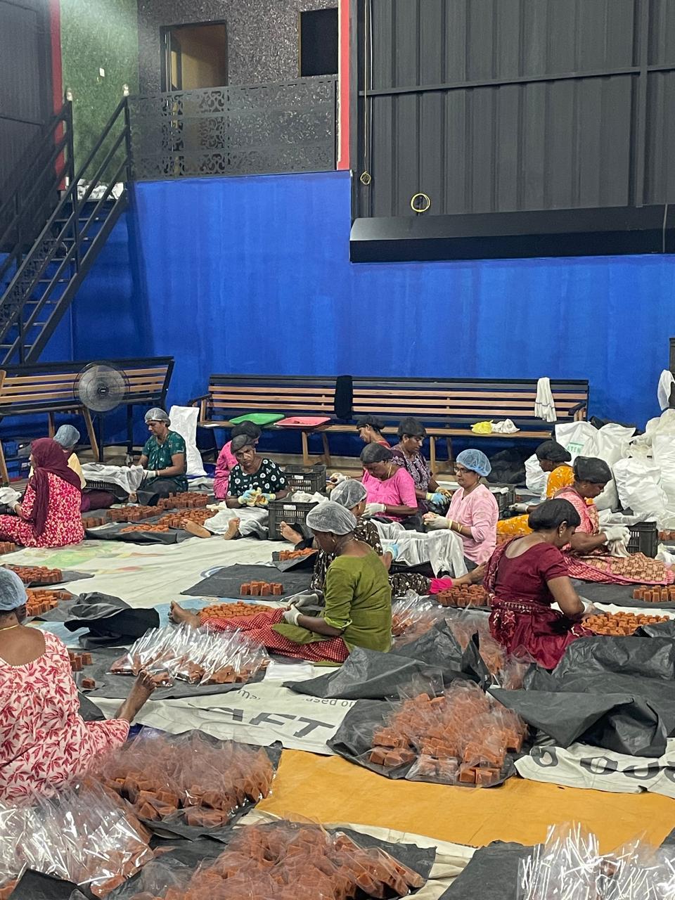 Workers in hairnets and gloves sorting and bagging jaggery cubes